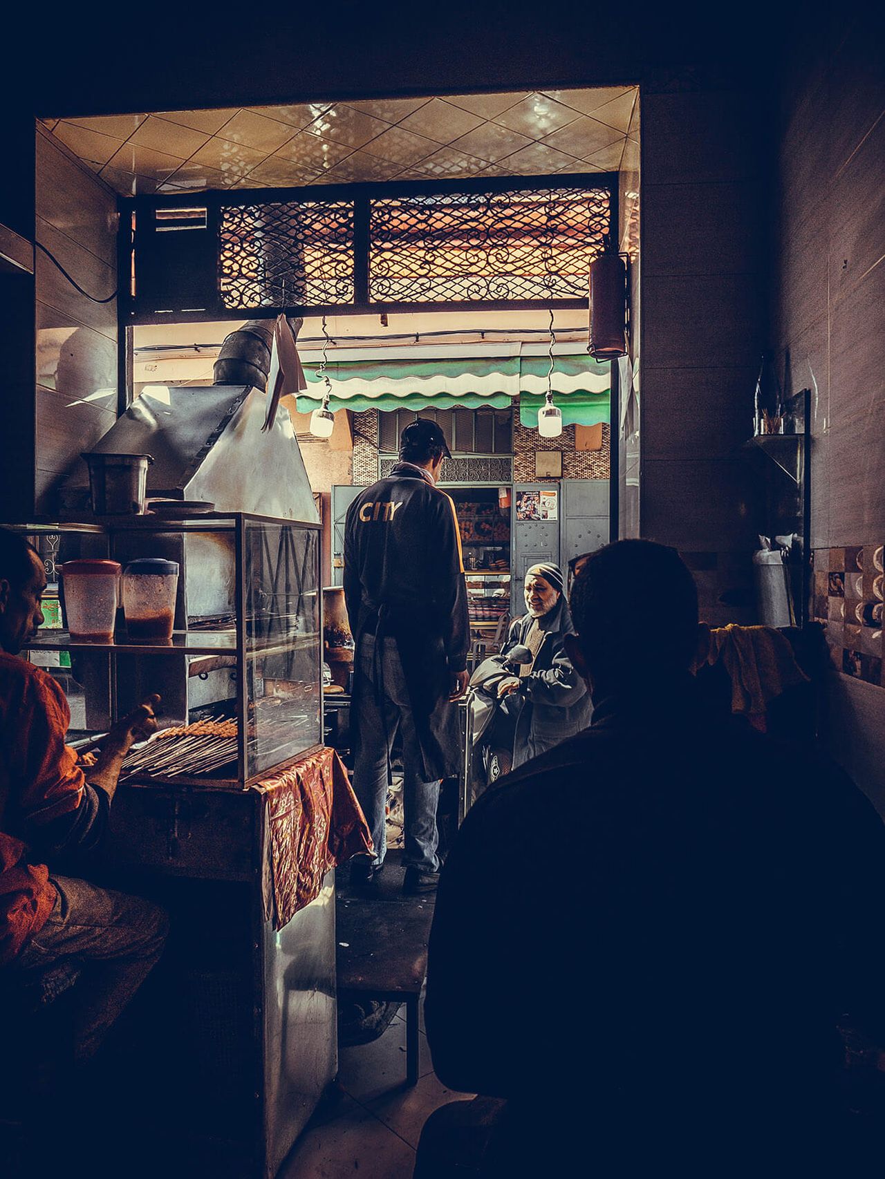 Looking into a crowded food stall framed by a dark doorway