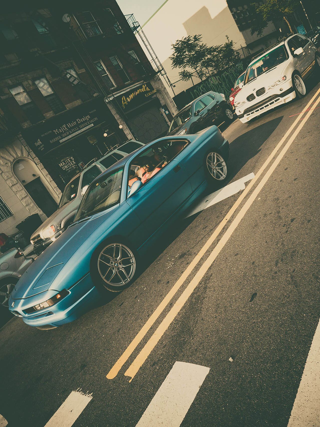 A blue sports car speeds across a city street with motion blur