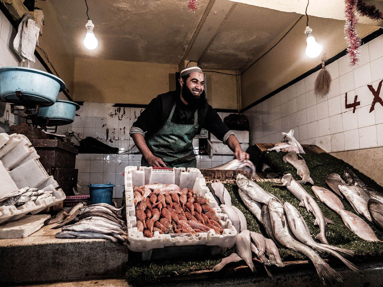 A fishmonger lays out the day's catch on a tiled market counter